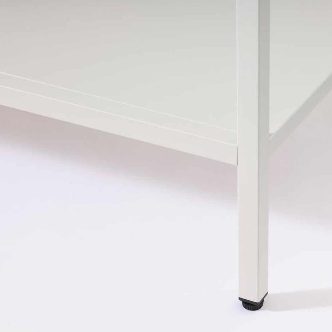 Carmel skap i lys greige, detalj av nedre hylle og ben mot hvit bakgrunn