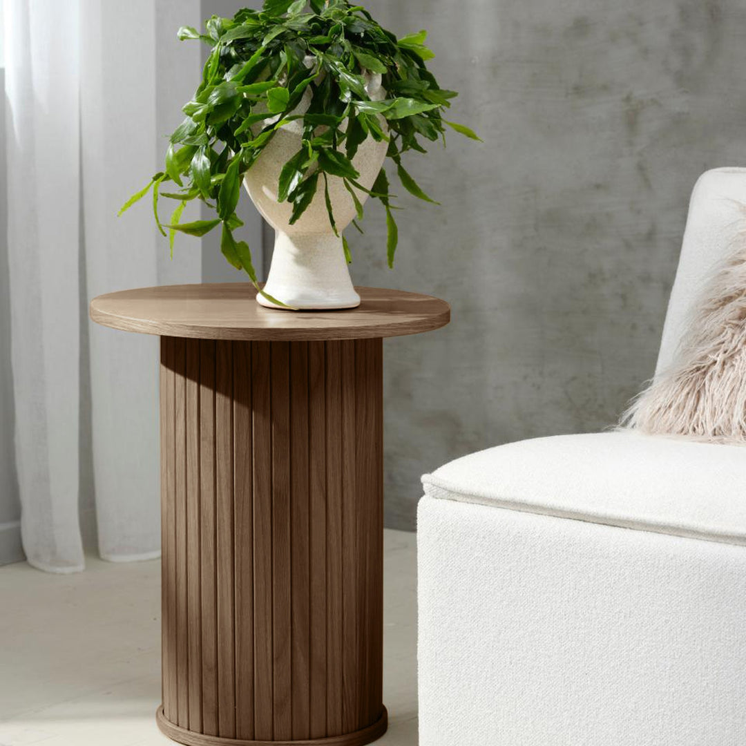 Fiola sidebord i røyket eik, rundt med riflet søylefot, ved hvit bouclésofa med plante i hvit krukke