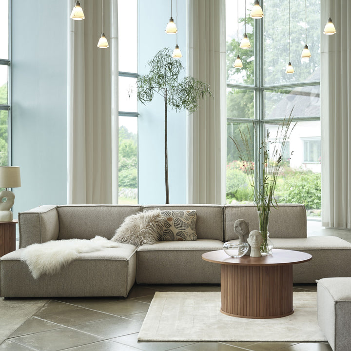 Fiola sidebord i røyket eik i lyst rom med beige modulsofa, saueskinn og store vinduer