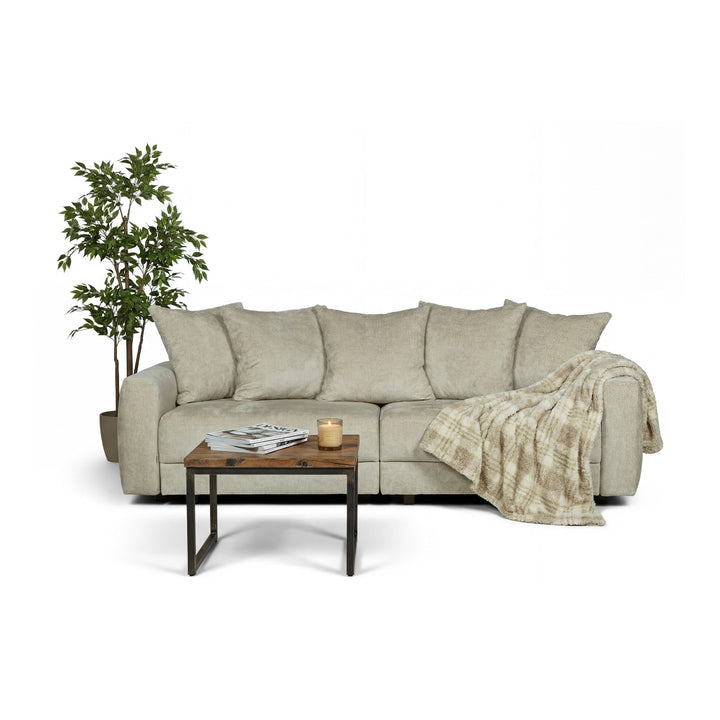Bellus Glory sovesofa i beige chenillestoff med pledd, sofabord og grønn plante