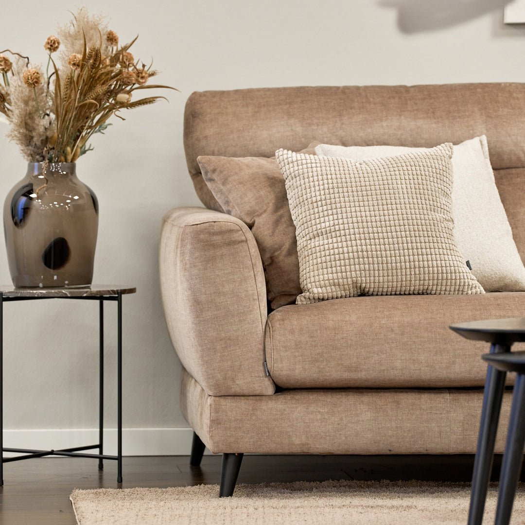 Bellus Robin sofa i gråbeige stoff med stripepute og brun vase med tørrblomster