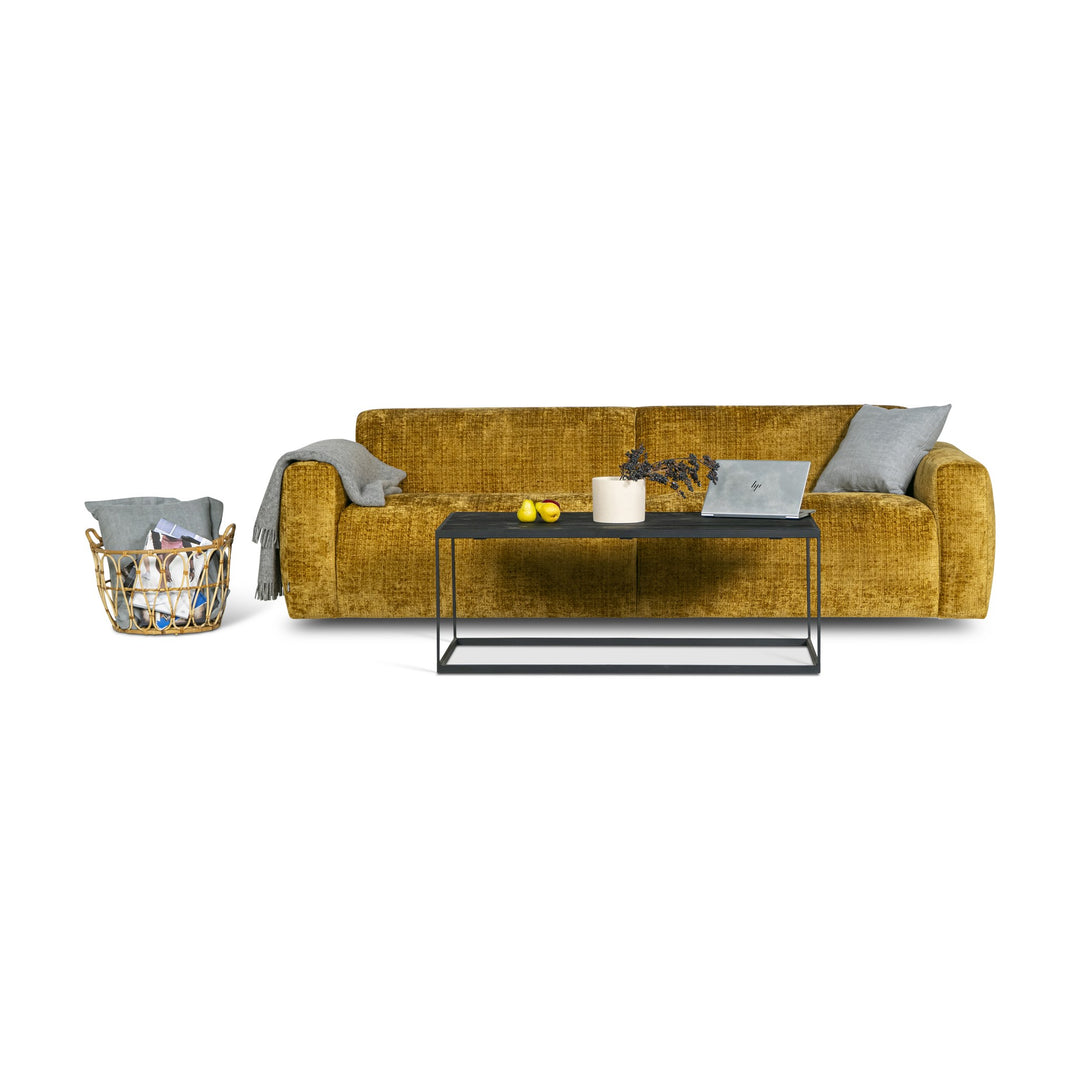 Bellus Olos sofa 3-seter i okergul chenille med pledd, kurv og svart sofabord i stue