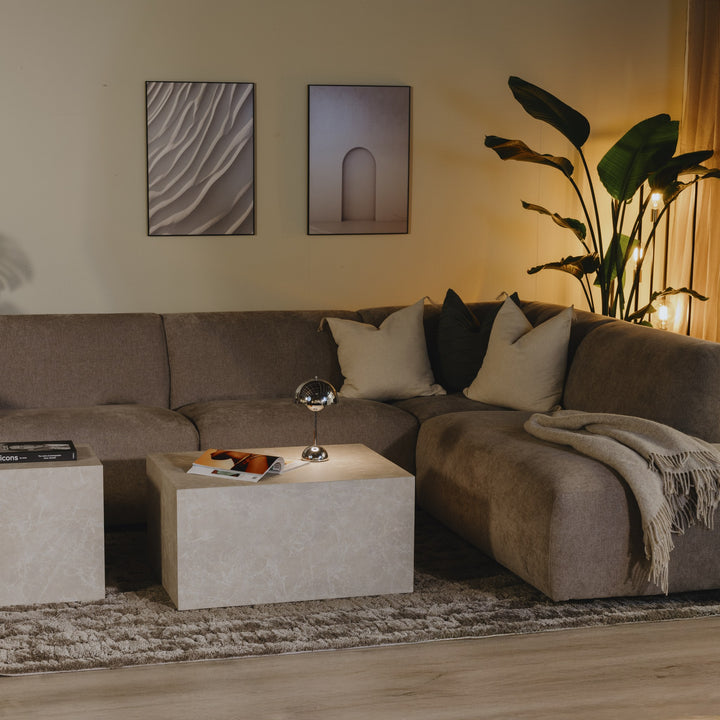 Bellus Olos hjørnesofa i lys grå chenille i stue med travertinbord, planter og veggkunst