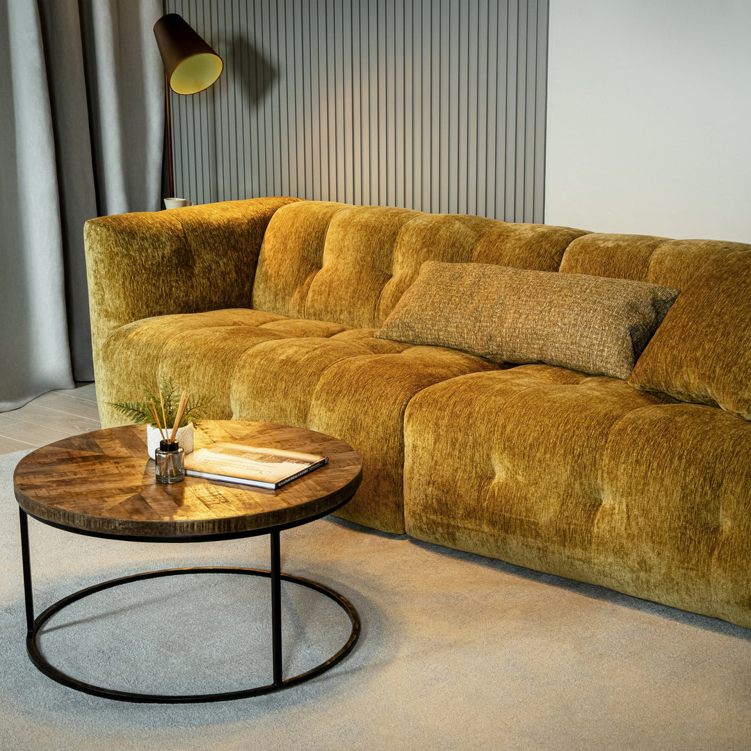 Bellus Soffy sofa i okergul chenille i stue med rundt trebord og gulvlampe ved panelvegg