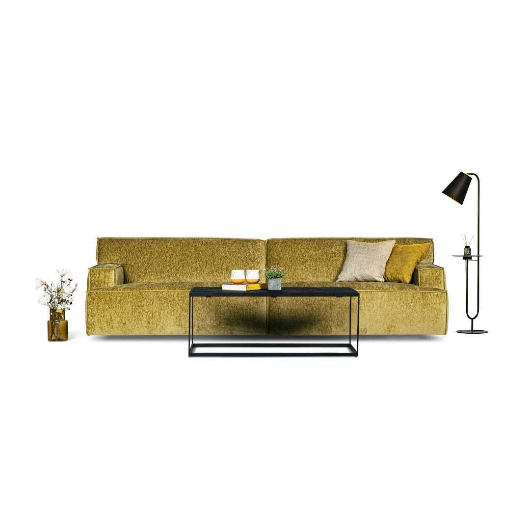 Bellus Mariposa sofa i okergul chenille med svart sofabord, gulvlampe og hvite blomster