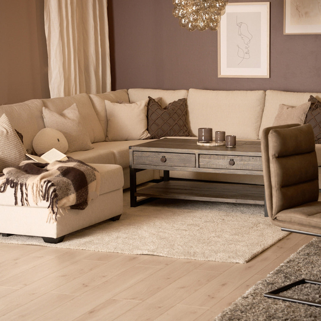 Bellus Casino modulsofa i beige i stue med trebord, brun lenestol og teppe