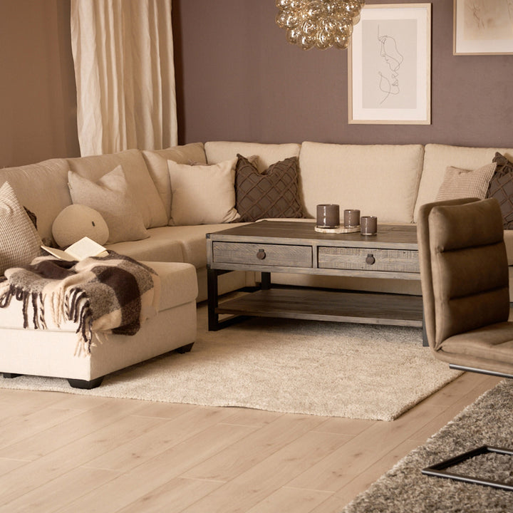 Bellus Casino modulsofa i beige i stue med trebord, brun lenestol og teppe