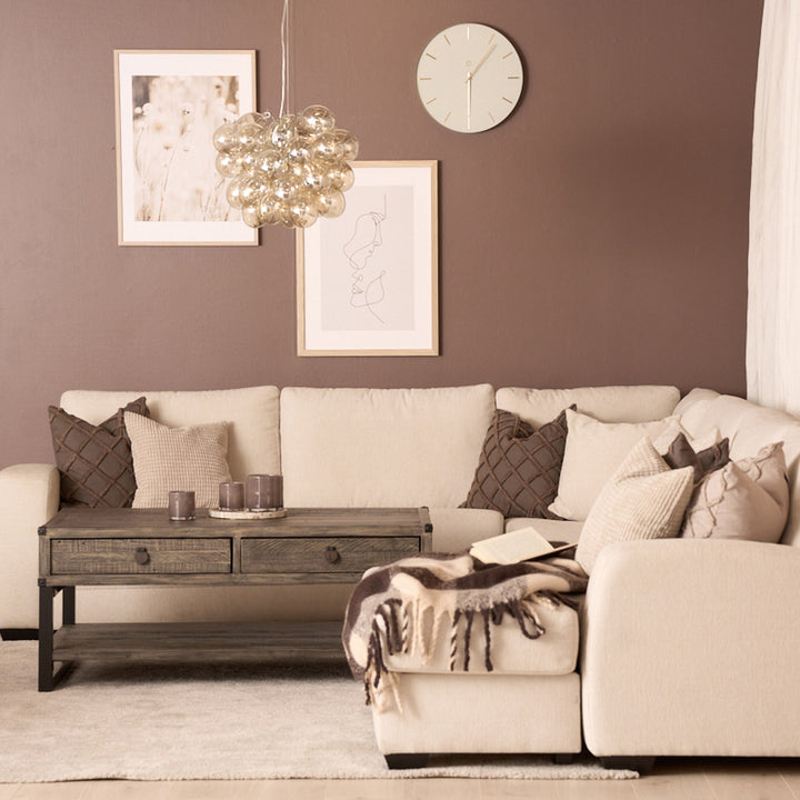 Bellus Casino modulsofa i beige i stue med brun vegg, trebord, klokke og kunst