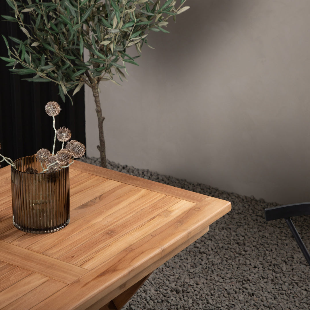 Venture Design Kenya spisebord i teak ute, med oliventre, brun vase og mørk småstein.