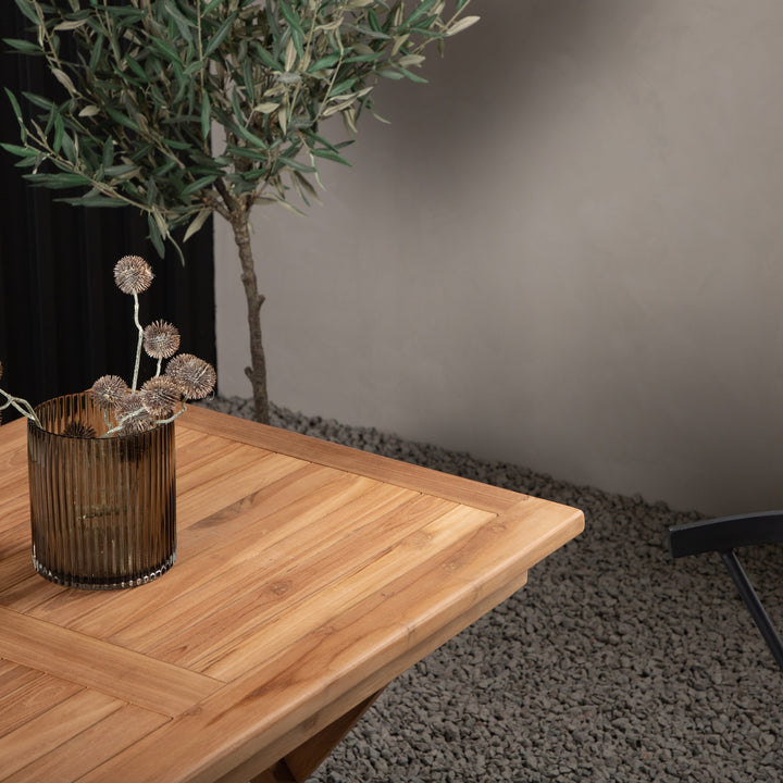Venture Design Kenya spisebord i teak ute, med oliventre, brun vase og mørk småstein.