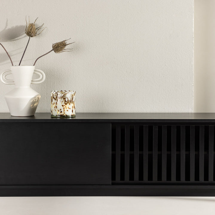 Lugo tv-benk i sort med spilefront, stylet med hvit vase og prikkete telysglass