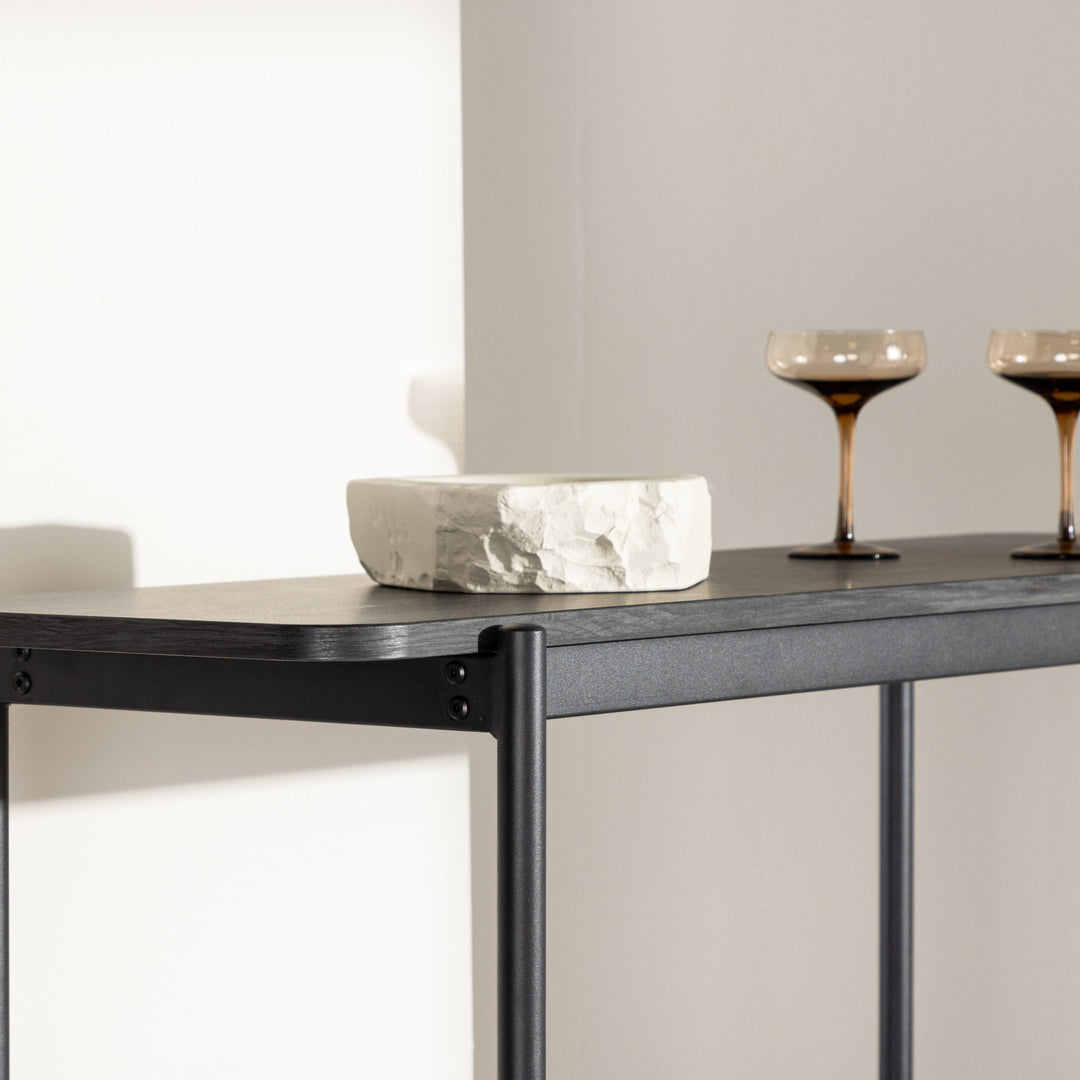 Heim hylle i sort med steinskål og to amberfargede glass på toppplaten