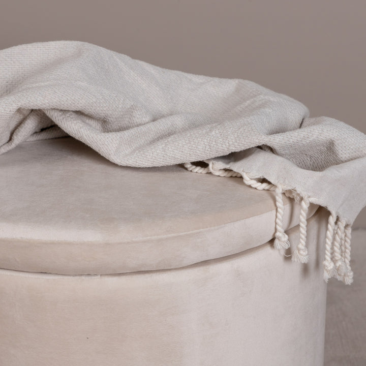 Dunken puff i beige fløyel, nærbilde av lokket med lyst frynsepledd drapert over