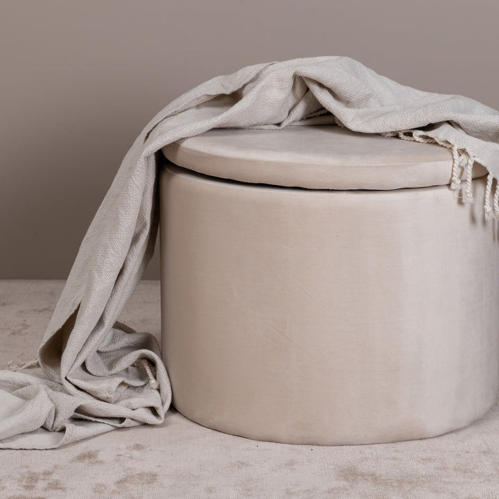 Dunken puff rund i beige fløyel med lokk, lyst linteppe drapert over