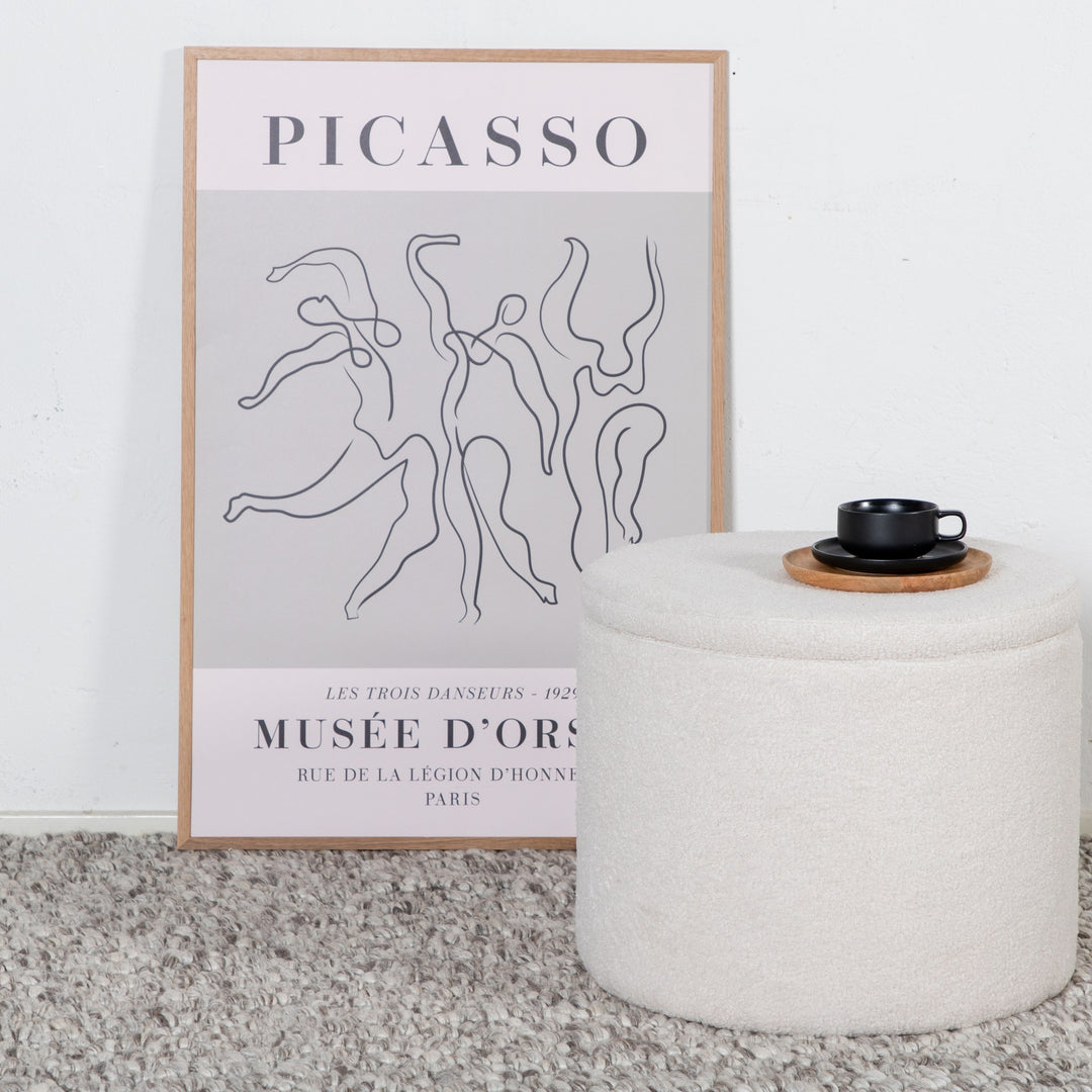 Dunken puff i offwhite bouclé med svart kopp på trefat, ved kunstplakat og grått teppe