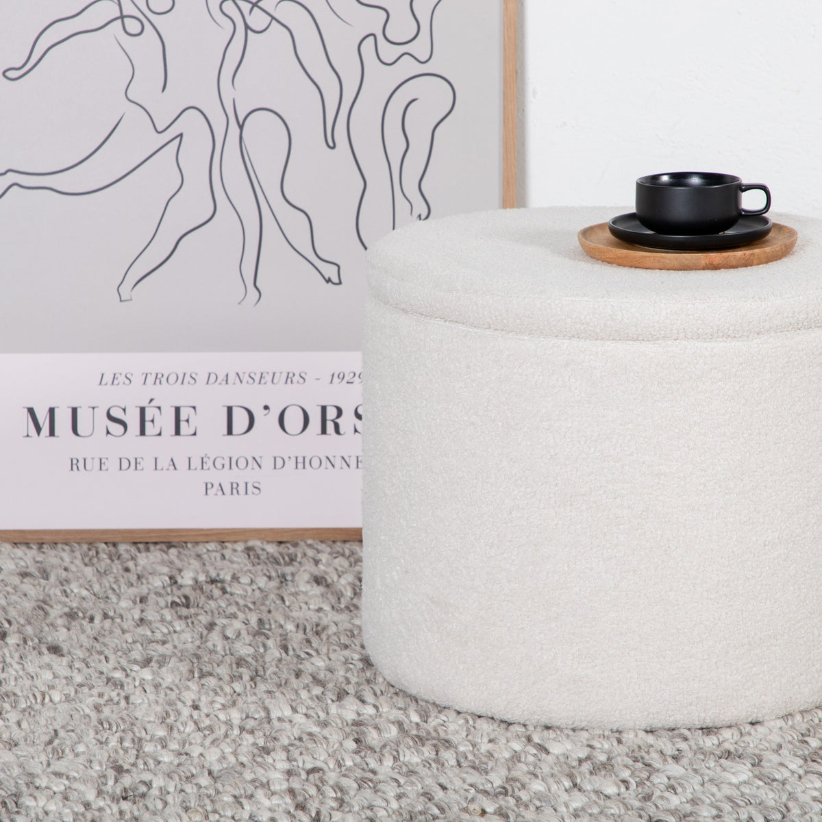 Dunken puff rund i offwhite bouclé med lokk, sort kopp på toppen, ved kunstplakat