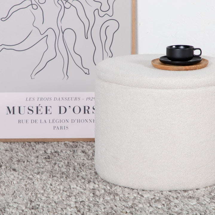Dunken puff rund i offwhite bouclé med lokk, sort kopp på toppen, ved kunstplakat