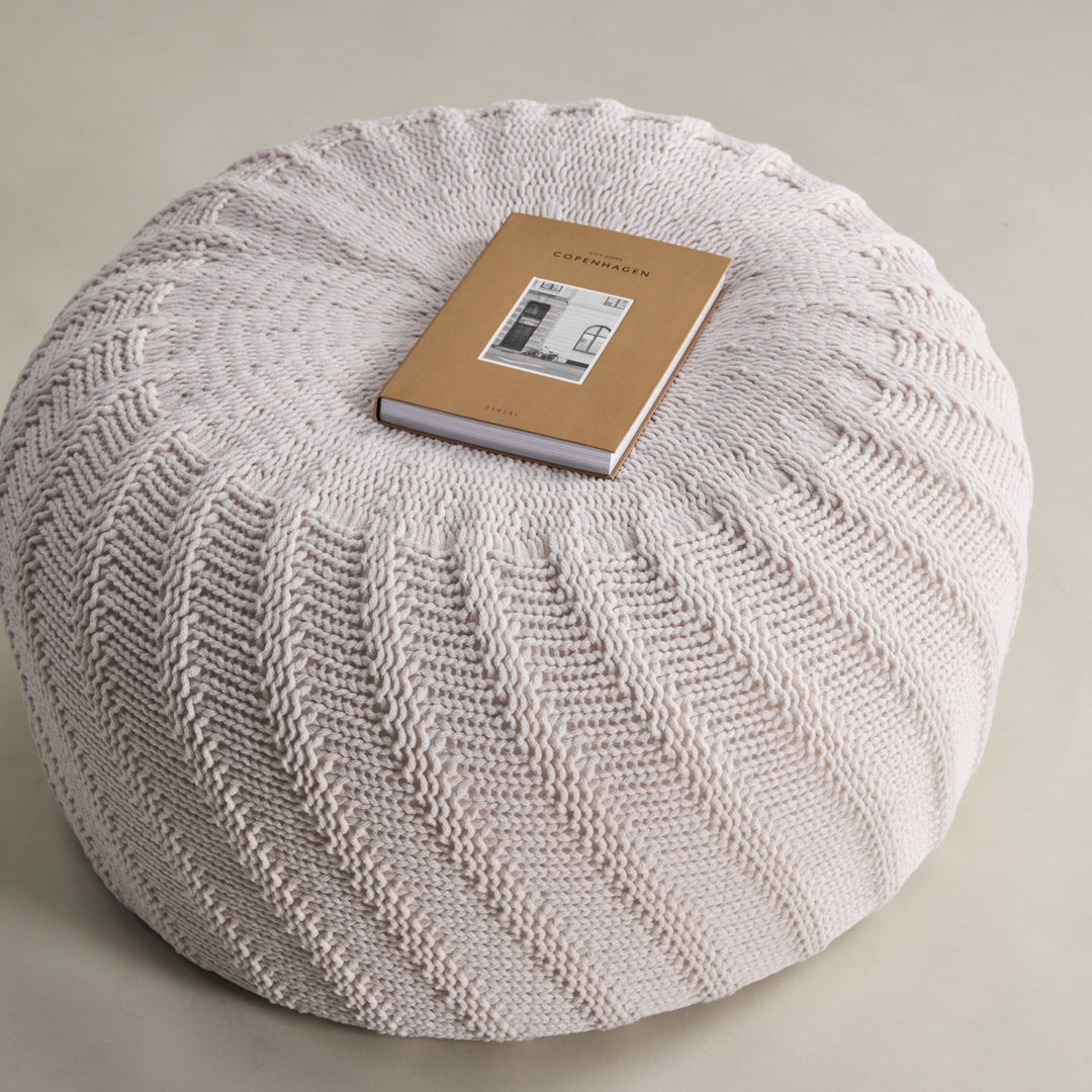 Ted puff i offwhite, sett ovenfra med spiralstrikk og bok på toppen.