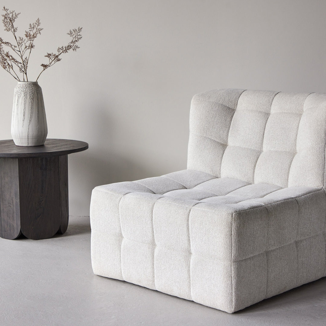 Malou loungestol i offwhite bouclé med rutet polstring, ved mørkt sidebord med vase