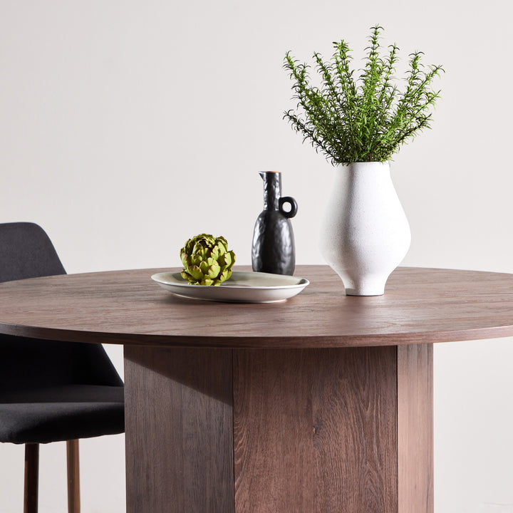 Tekla spisebord i mocca, brun treplate med hvit vase, sort kanne og dekorfat med artisjokk