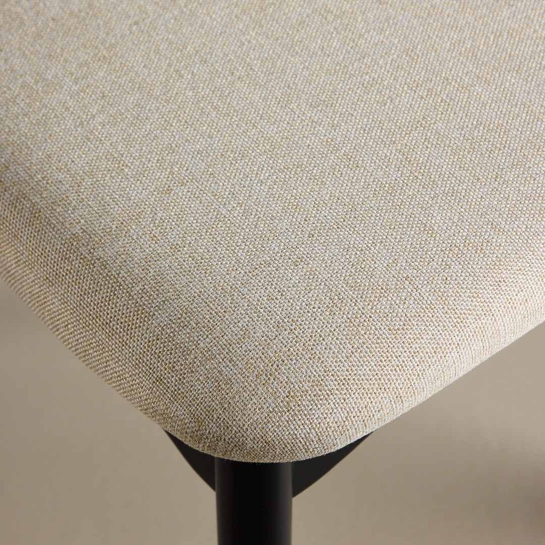 Ven spisestol, nærbilde av beige stofftrekk på sete med sort metallben