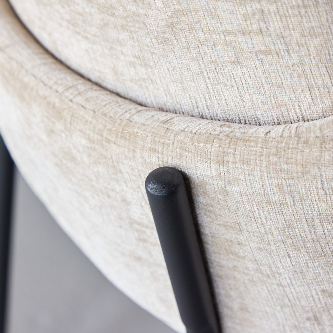 Blom spisestol i beige chenille, nærbilde av sete og sort metallben.