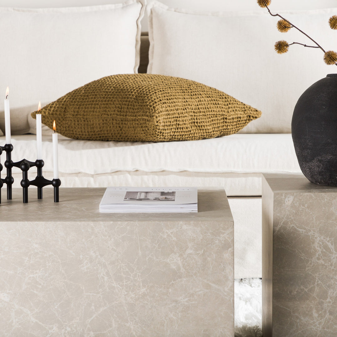 York sofabord i beige marmorlook med telys, magasin og sort vase foran lys sofa