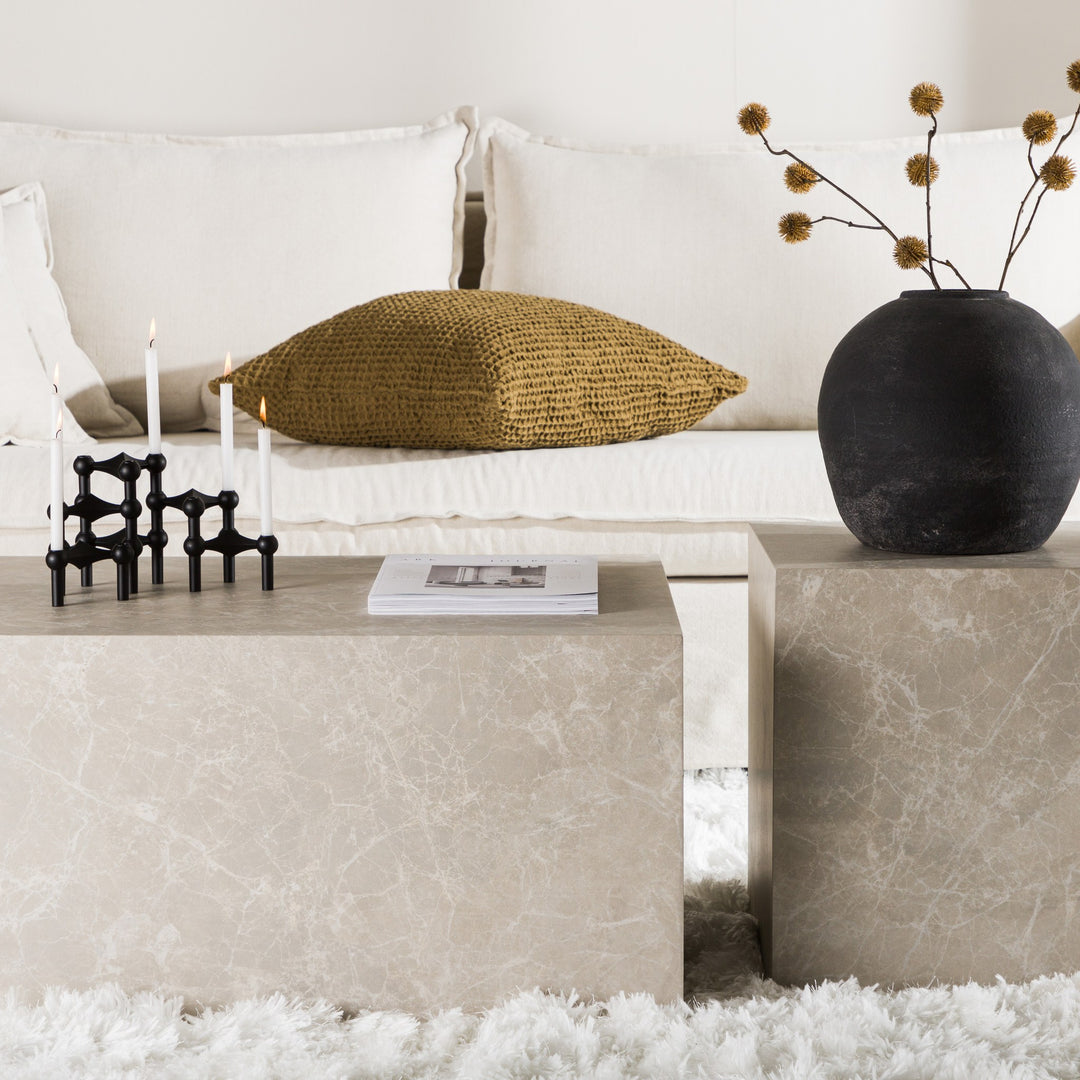 York sofabord i beige marmorlook med telys, bok og sort vase foran beige sofa