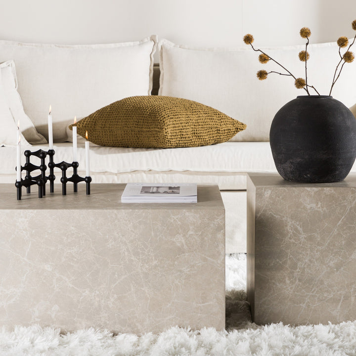 York sofabord i beige marmorlook med telys, bok og sort vase foran beige sofa