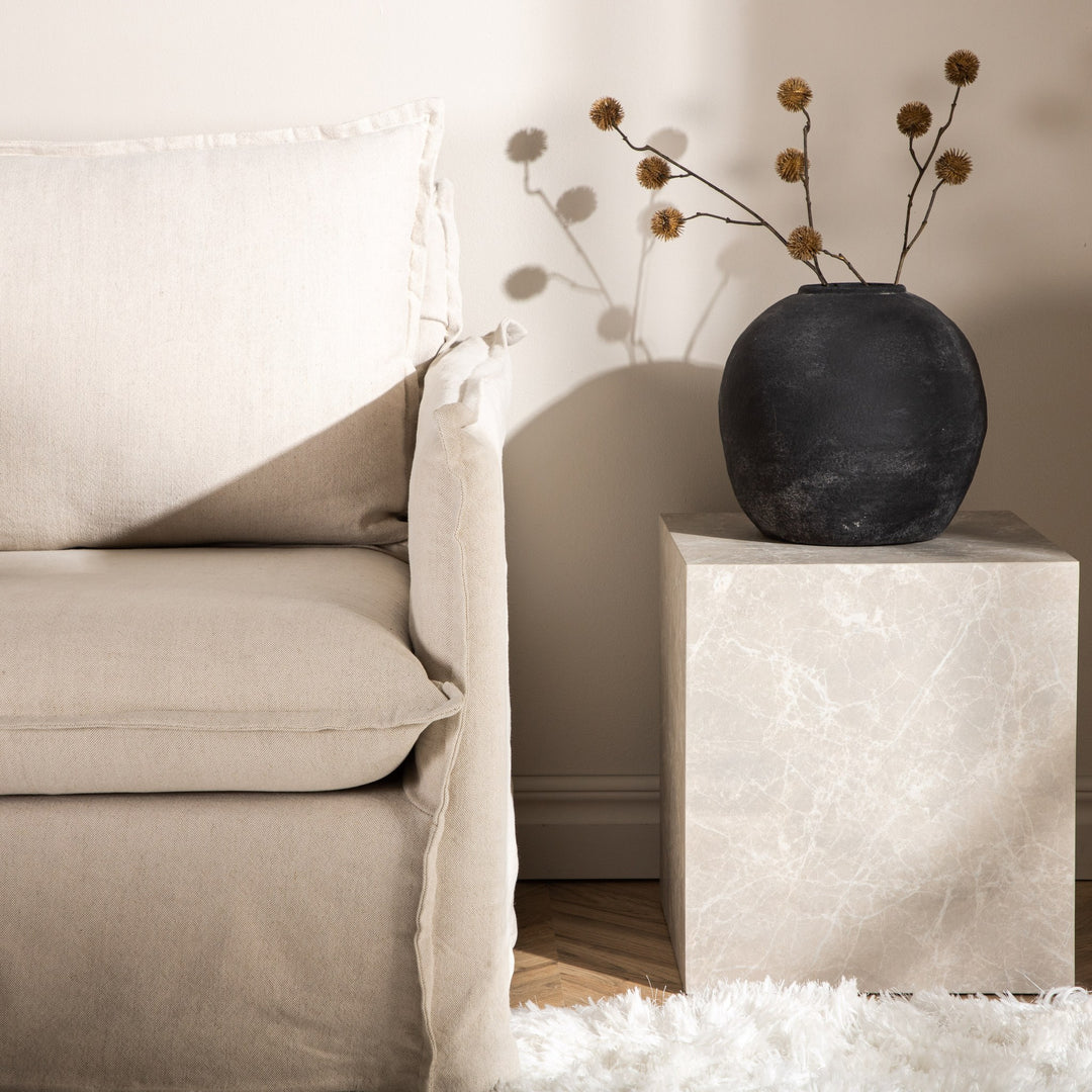 York sofabord i beige marmorlook med sort vase og tørrkvister ved beige sofa