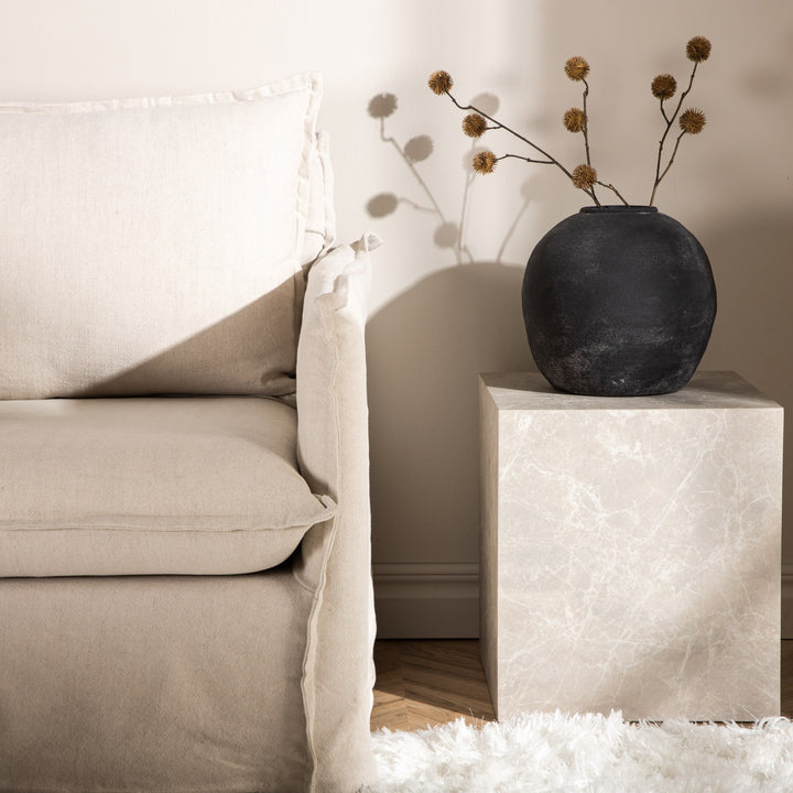 York sofabord i beige marmorlook med sort vase og tørrkvister ved beige sofa