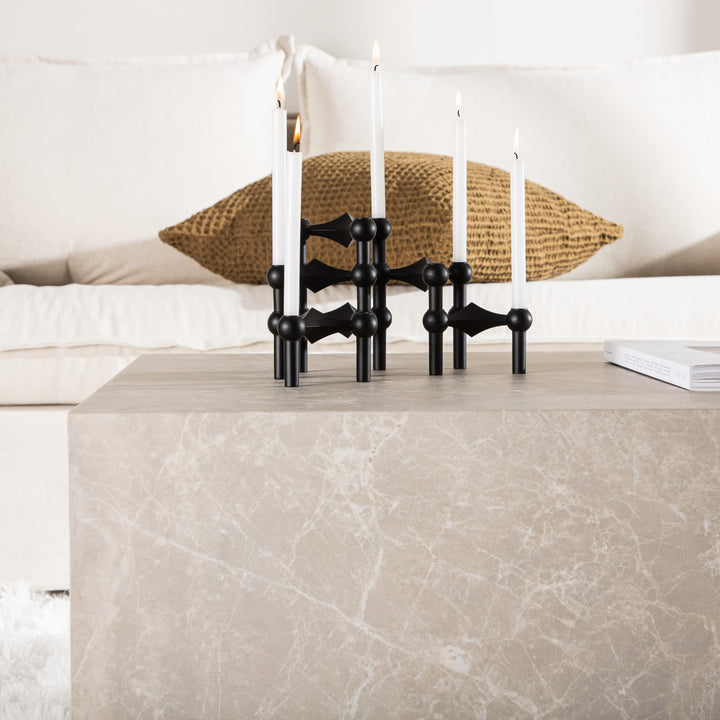 York sofabord i beige marmorlook med sort lysestake og hvite lys foran lys sofa