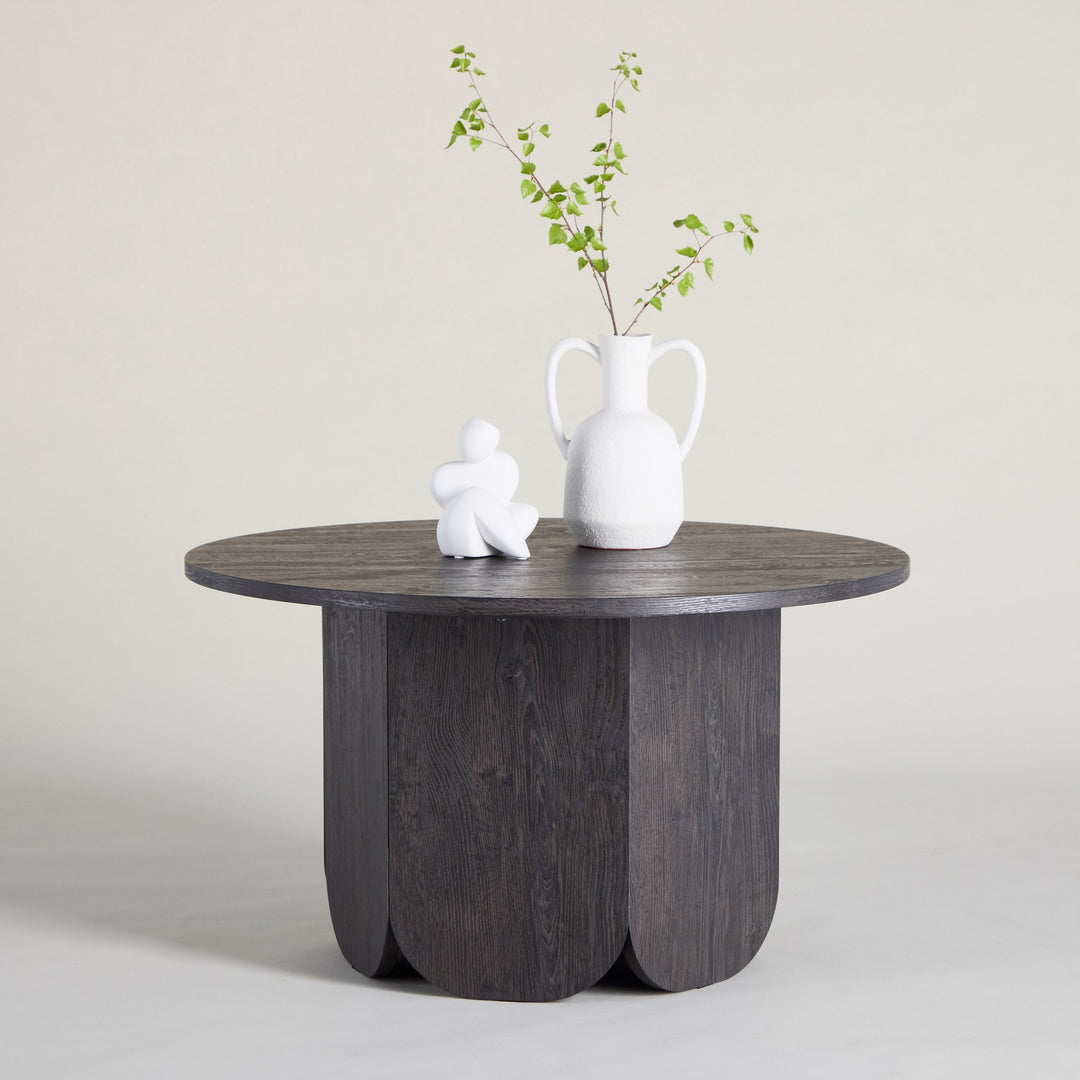 Tekla sofabord i sort, rundt med buet base, hvit skulptur og vase med grønne grener