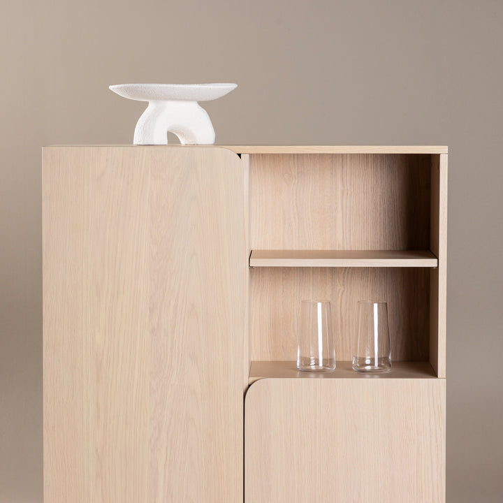 Tyresø skap i kalket eik med hvit skulptur på toppen og glass i åpen hylle, mot beige vegg