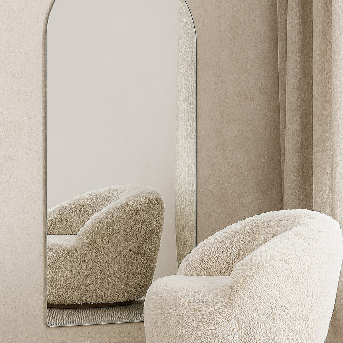 Sarasota speil med bueform mot vegg, foran beige teddystol og lyst gardin