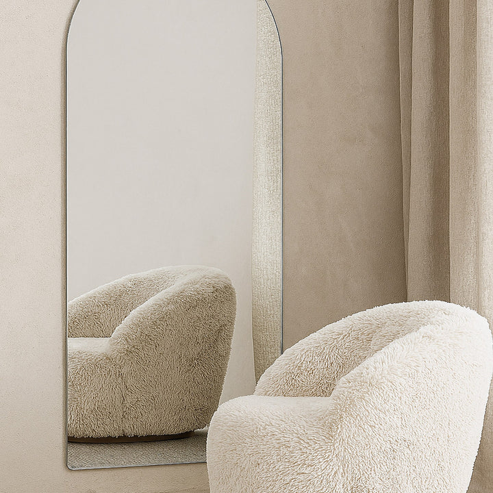 Sarasota speil med bueform mot vegg, foran beige teddystol og lyst gardin