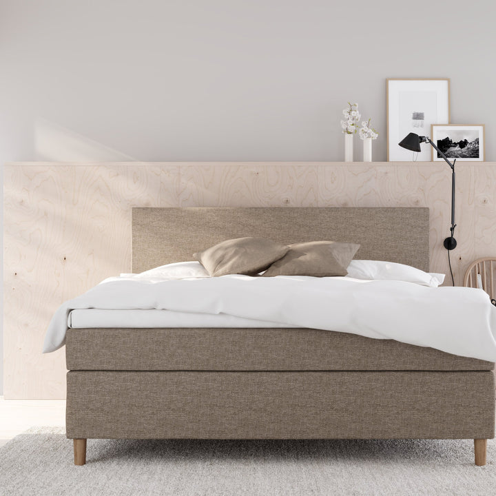 Wonderland Medley kontinentalseng i beige stoff i lyst soverom med finérvegg, hvit dyne og grått teppe